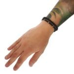 Założony na ręce zestaw bransoletek dla mężczyzny z czarnego onyksu i srebrnych przekładek z motywem dolara