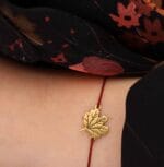Bransoletka na jesień na sznurku liść klonu srebrna pozlacana na ręce Bransoletka na jesień z liściem klonu srebrna pozłacana na bordowym sznurku założona na ręce