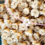 Damska bransoletka na różowym sznurku z kwiatkiem z masy perłowej i srebra pozłacanego wśród suszonych kwiatów