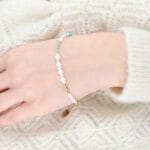 Bransoletka z zielonym amazonitem i białą masą perłową założona na ręce. Bransoletka srebrna pozłacana regulowana