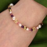 Kolorowa bransoletka z kamieniami i perłą na ręce