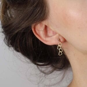 Damskie kolczyki wiszące celebrytka w kształcie serc założone na uchu. Kolczyki srebrne pozłacane