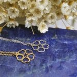 Dwa naszyjniki celebrytka z sercami w formie srebrnej i pozłacanej. Naszyjniki leżą na lapis lazuli