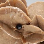 Elegancki i gustowny damski naszyjnik pozłacany z bryłką czarnego onyksu na róży pustyni