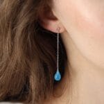 Damskie kolczyki długie wiszące z niebieskim chalcedonem. Kolczyki srebrne pozłacane na sztyfcie założone na ucho