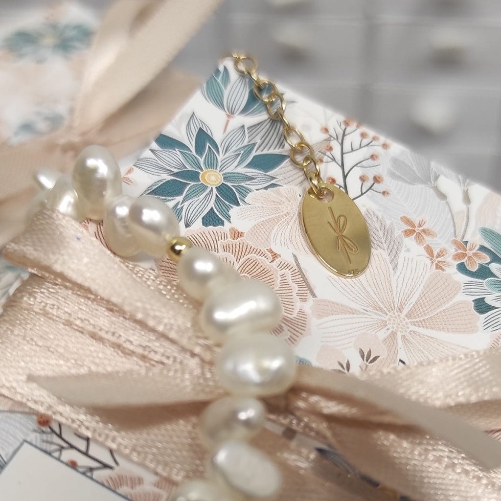 Logo rosett wygrawerowane na dopince przy bransoletce z perłami