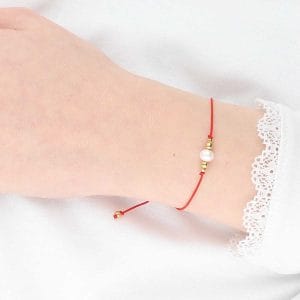 Elegancka i minimalistyczna bransoletka na czerwonym sznurku z perła i kuleczkami srebra pozłoconego