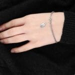 Damska bransoletka z hematytem w formie kulek gładkich oraz elementów ze srebra próby 925 założona na ręce