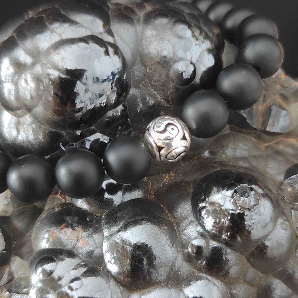 elastyczna bransoletka męska onyks z jin jang ze srebra leżąca na hematycie