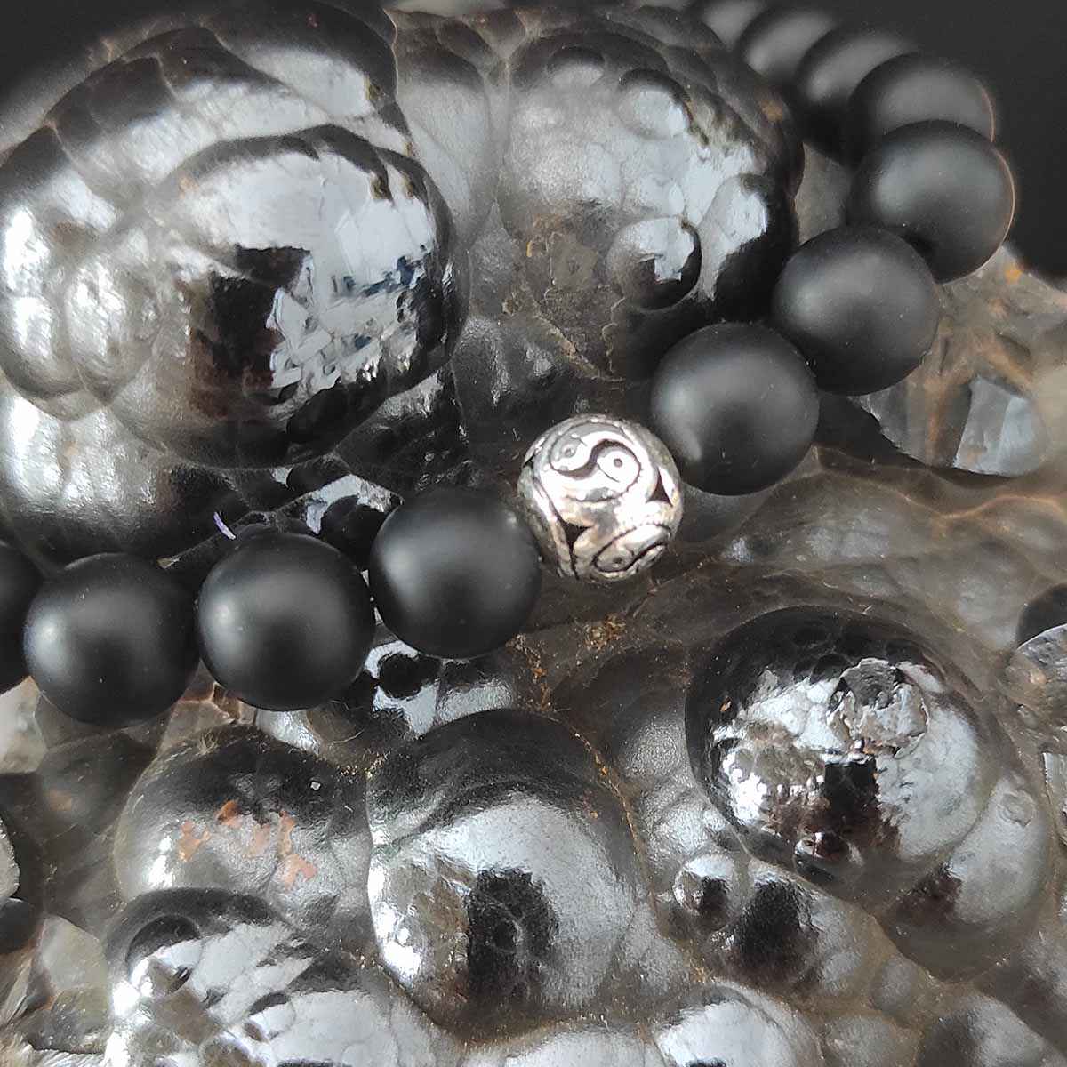 elastyczna bransoletka męska onyks z jin jang ze srebra leżąca na hematycie