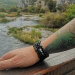 Zestaw męskich bransoletek założonych na ręce które wykonane są z kamieni naturalnych takich jak agat, hematyt, onyks