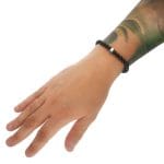 Założona na ręce męska elastyczna bransoletka z czarnego fasetowanego onyksu i czaszki odlanej ze srebra 925