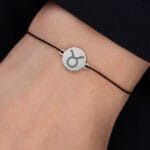 Damska bransoletka dla Byka na czarnym sznurku z celebrytką z grawerem znaku zodiaku Byk na ręce