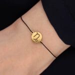 Bransoletka dla Koziorożca czarny sznurek z celebrytką. Bransoletka srebrna pozłacana na czarnym sznurku na ręce