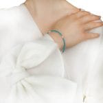 Damska bransoletka srebrna pozłacana z kuleczek turkusu i pereł założona na ręce