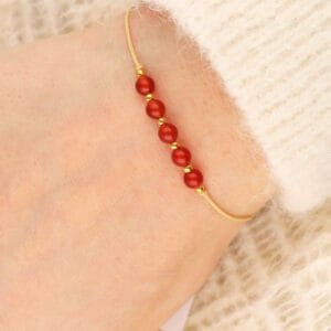 Damska beżowa bransoletka sznurkowa z pomarańczowym kamieniem karneol na ręce