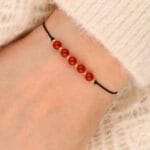 Damska bransoletka na sznureczku z pomarańczowym kamieniem karneol na ręce