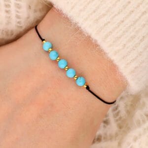 Damska bransoletka na sznureczku z niebieskim kamieniem turkus na ręce