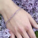 Założona na rękę bransoletka srebrna dla kobiety z kuleczkami ametystu oraz dodatkowym łańcuszkiem ze srebra.