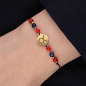 Bransoletka dla Byka na sznurku z celebrytką, koralem, karneolem i lapisem lazuli założona na ręce