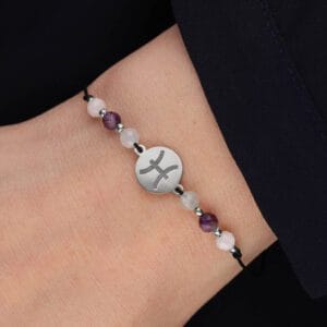 Srebrna bransoletka dla Ryb na czarnym sznurku z celebrytka i akwamarynie, kamieniem księżycowym i ametystem założona na ręce