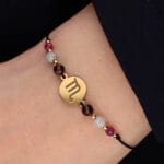 Bransoletka dla Skorpiona na sznurku z celebrytką, granatem, akwamarynem i rubinem założona na ręce