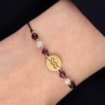 Bransoletka dla Wodnika na sznurku z celebrytką, ametystem, akwamarynem i granatem założona na ręce