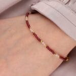 Pozłacana bransoletka z małych kuleczek kwarcu różowego i granatu na ręce