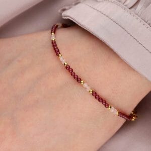 Pozłacana bransoletka z małych kuleczek kwarcu różowego i granatu na ręce