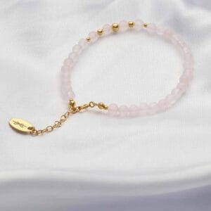 Bransoletka z różowym kwarcem i srebra pozłacanego. Bransoletka regulowana leżąca na płótnie