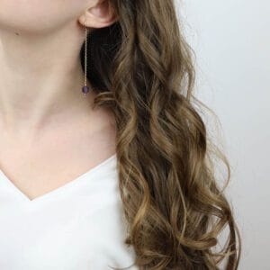 Długie kolczyki z fioletowym ametystem na łańcuszku ankier założone na uchu