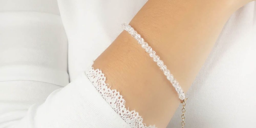 Bransoletka damska srebrna pozłacana z popękanym naturalnym kwarcem założona na rękę. Bransoletka posiada przedłużkę na której końcu zawieszona jest zawieszka z logo Rosett