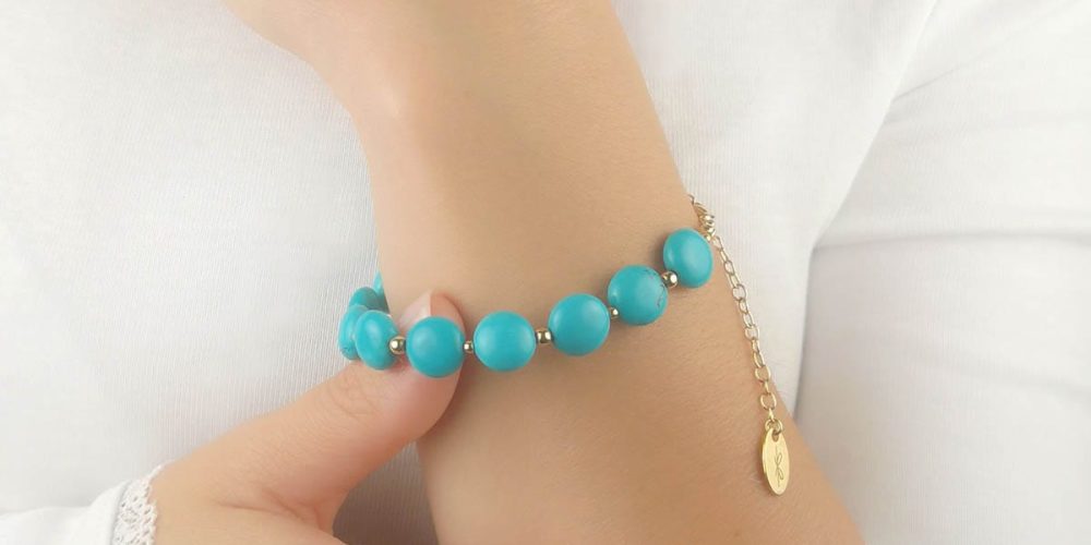 Damska bransoletka turkus srebrna pozłacana założona na rękę. Bransoletka posiada przedłużkę na której końcu zawieszona jest zawieszka z logo Rosett