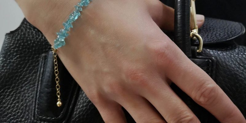 Ubrana na rękę trzymająca torebkę złota bransoletka damska goldfilled z sieczką z apatytu i przedłużką zakończoną kuleczka