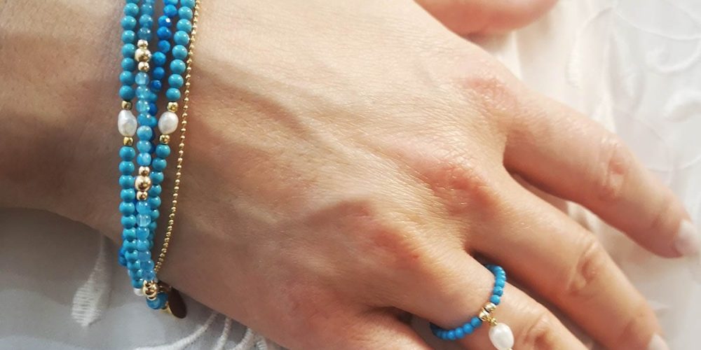 Zestaw bransoletek i pierścionka elastycznego założony na rękę, wykonany z turkusów, naturalnych pereł i kuleczek srebra pozłacanego