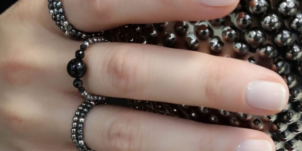 Zestaw pięknych ciemnych pierścionków elastycznych z onyksu, spinela i hematytu założone na palce