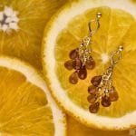 Kolczyki sztyfty srebrne pozłacane z wiszącymi kwarcami dymnymi leżące na cytrynach