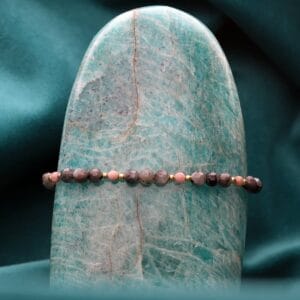 Bransoletka damska pozłacana z kamieniem naturalnym labradoryt i rodonit na sznurku w szarym kolorze zawieszona na kamieniu