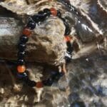 Męska bransoletka z kamieni naturalnych pomarańczowy agat i czarny onyks położona w małej rzeczce