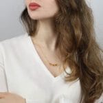 Delikatny naszyjnik z pozłacanego łańcuszka z zawieszkami z cytrynu naturalnego, prezentowany na modelce o kasztanowych lokach i białej bluzce z głębokim dekoltem.