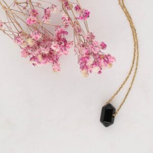 Pozłacany naszyjnik z czarnym onyksem w kształcie grota na tacy