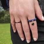 Złoty pierścionek elastyczny z kuleczką złota i czarnym onyksem i innymi pierścionkami elastycznymi założone na palcu