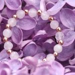 pierścionek elastyczny srebrny pozłacany z kwarcem różowym położony na kwiatach