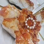 Damski stylowy i elegancki pierścionek elastyczny z naturalnych pereł i kuleczek gold filled położony na kryształach cytrynu